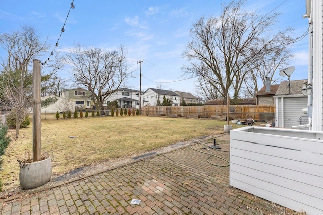 view of yard featuring a residential view, fence, and a patio