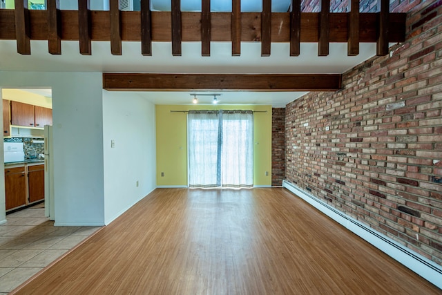 unfurnished living room featuring beam ceiling, baseboard heating, brick wall, light wood-type flooring, and baseboards