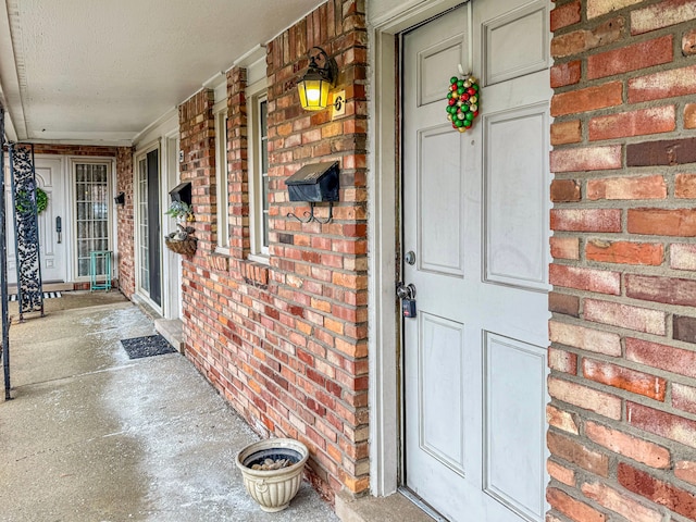 property entrance with a porch and brick siding