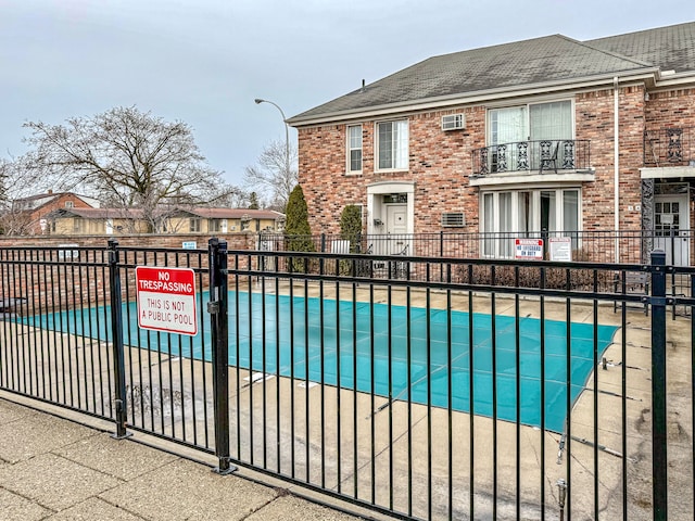 view of swimming pool with a wall mounted air conditioner and fence