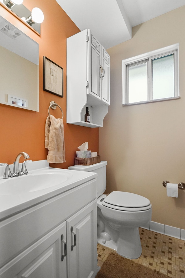 bathroom featuring toilet, vanity, visible vents, and baseboards