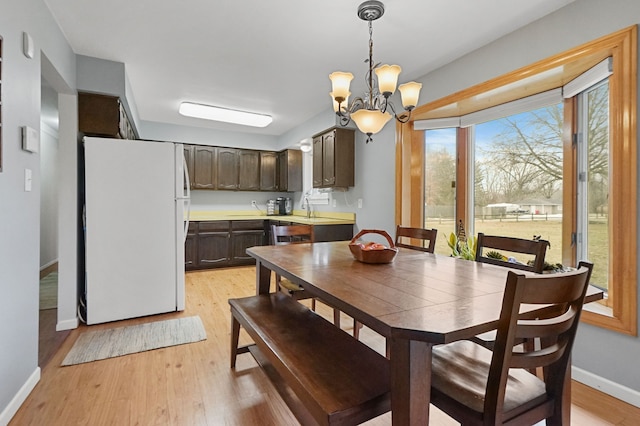 dining space featuring baseboards, a chandelier, and light wood-style floors