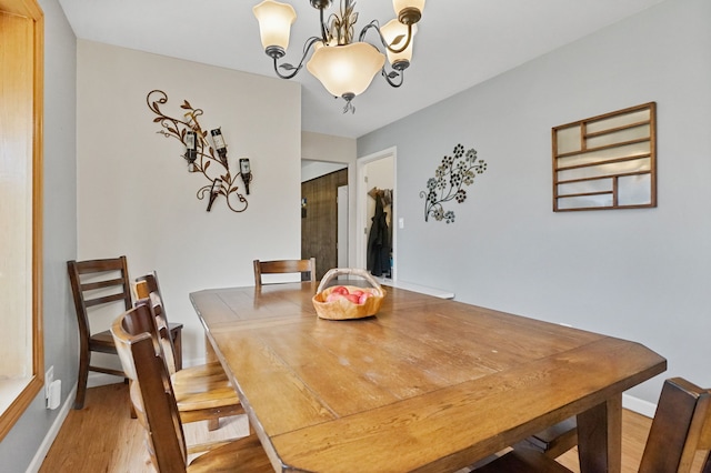 dining area with a chandelier, light wood-style flooring, and baseboards