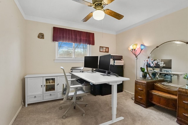 home office featuring ceiling fan, baseboards, crown molding, and light colored carpet