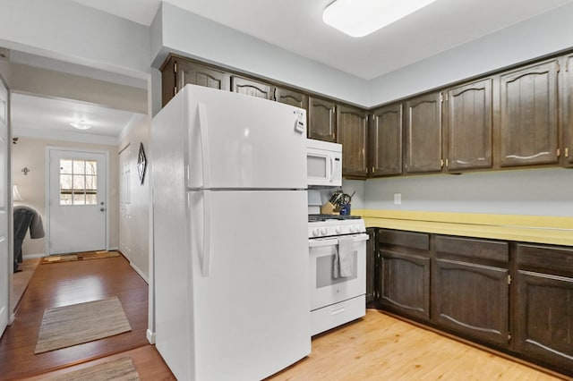 kitchen with white appliances, light countertops, dark brown cabinetry, and light wood-style flooring