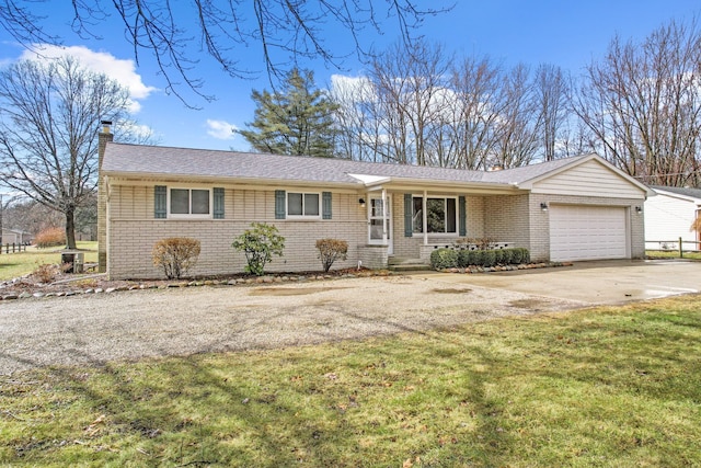 single story home featuring driveway, a chimney, an attached garage, a front yard, and brick siding