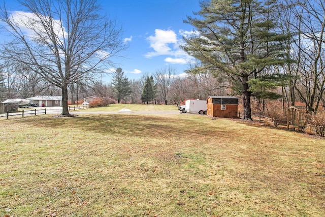 view of yard with a shed, an outdoor structure, and fence