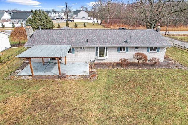 rear view of house with a patio area, a lawn, a chimney, and roof with shingles