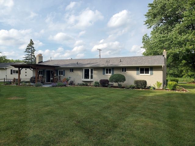 back of house featuring a patio, a chimney, a lawn, and brick siding