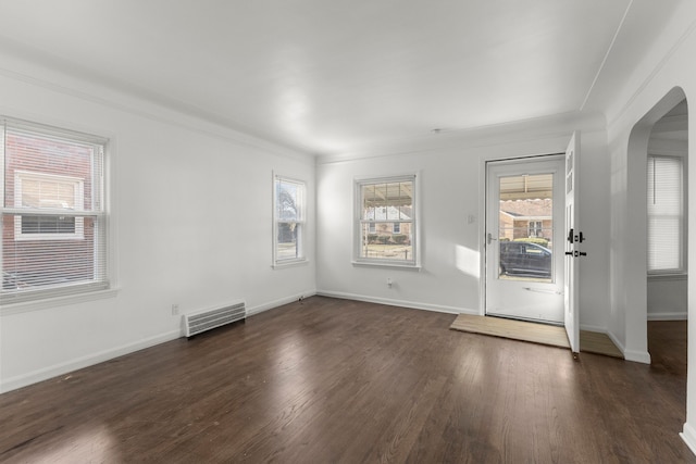 unfurnished room with visible vents, arched walkways, baseboards, and wood finished floors