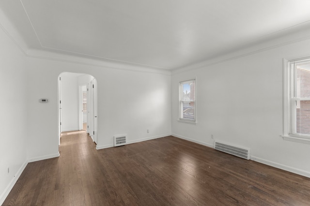 empty room with arched walkways, visible vents, and a wealth of natural light