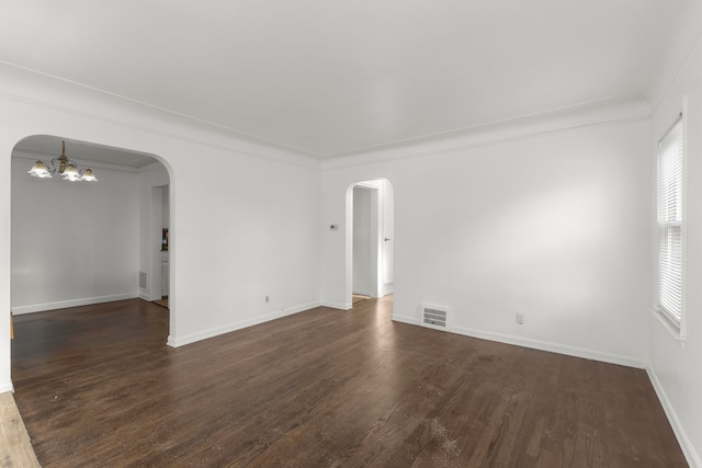 spare room featuring visible vents, baseboards, dark wood finished floors, arched walkways, and a notable chandelier