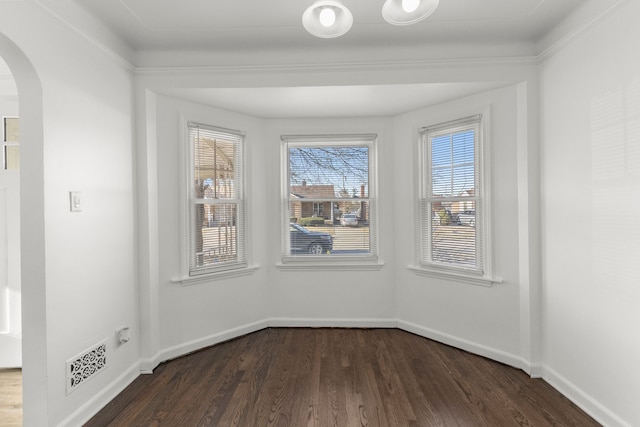 unfurnished dining area featuring arched walkways, visible vents, baseboards, and dark wood-style floors