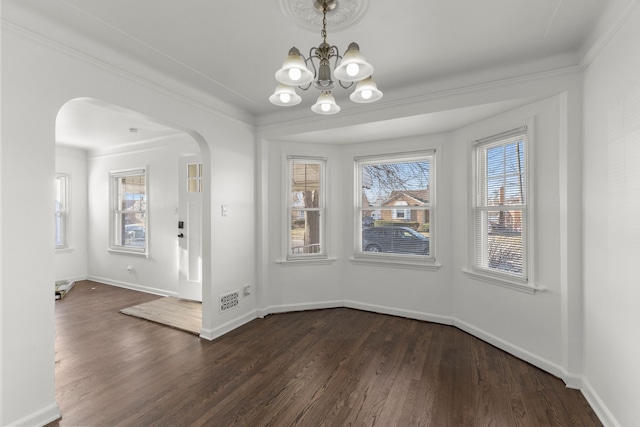 unfurnished dining area with an inviting chandelier, baseboards, arched walkways, and dark wood-type flooring