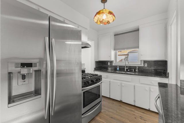 kitchen with under cabinet range hood, backsplash, appliances with stainless steel finishes, and a sink