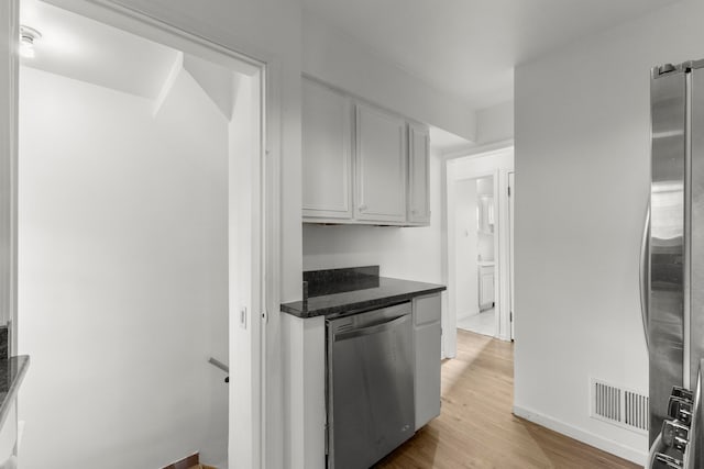 kitchen with visible vents, light wood-style flooring, white cabinetry, stainless steel appliances, and baseboards