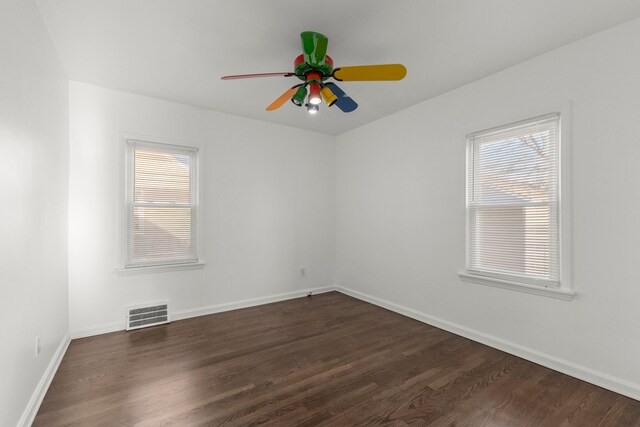 spare room with baseboards, visible vents, dark wood-style flooring, and ceiling fan