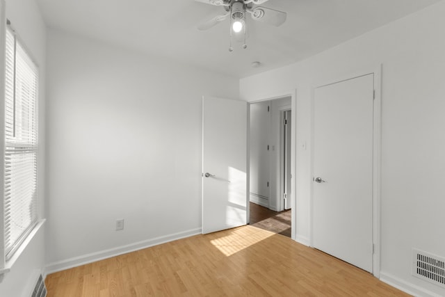 unfurnished bedroom featuring ceiling fan, visible vents, baseboards, and wood finished floors