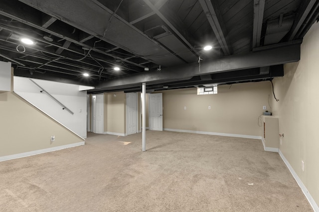 below grade area featuring light colored carpet and baseboards