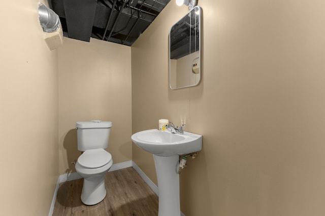 half bath featuring a sink, toilet, baseboards, and wood finished floors