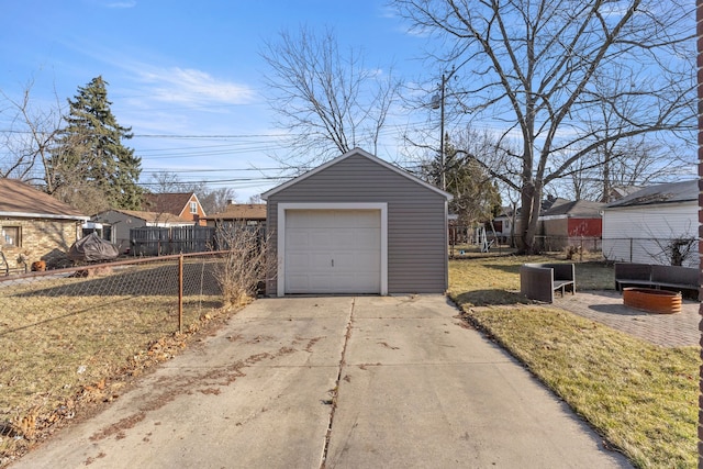 detached garage featuring concrete driveway and fence