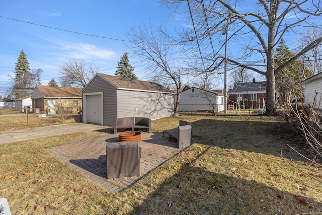 view of yard with a garage, an outbuilding, driveway, and fence