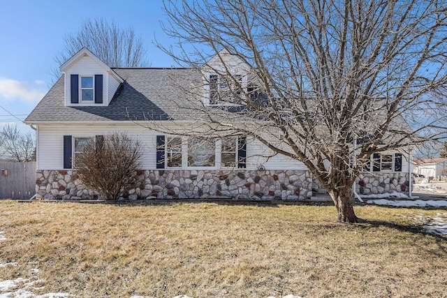 view of front facade with stone siding, a front lawn, and a shingled roof