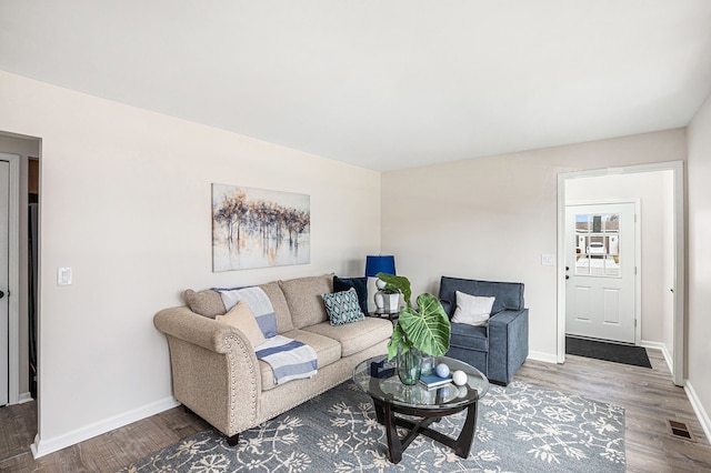 living area with visible vents, baseboards, and wood finished floors