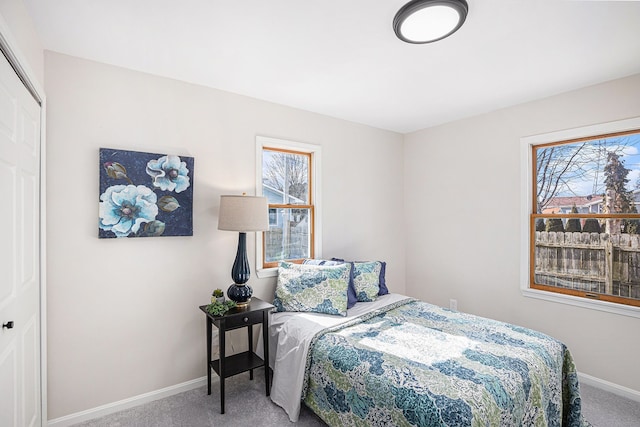 carpeted bedroom with baseboards, multiple windows, and a closet