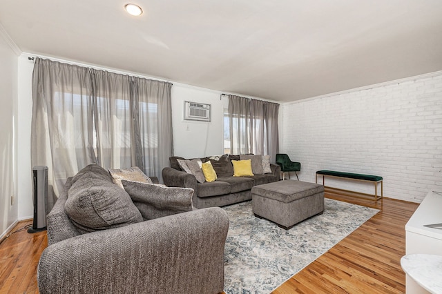 living room featuring a wall mounted air conditioner, light wood finished floors, and brick wall