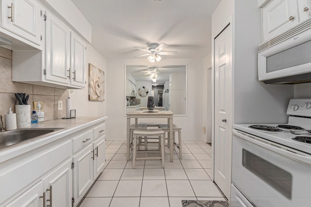 kitchen with white appliances, decorative backsplash, light countertops, white cabinetry, and light tile patterned flooring