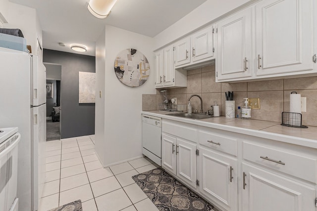 kitchen with backsplash, light tile patterned flooring, a sink, white cabinets, and white appliances