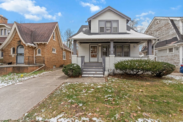 bungalow-style house featuring covered porch and a front lawn