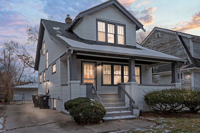 view of front of home featuring covered porch, a chimney, and roof with shingles