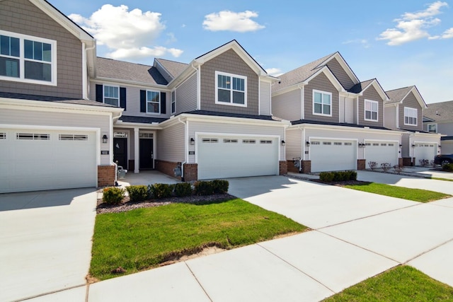 townhome / multi-family property featuring a garage, driveway, a front lawn, and brick siding