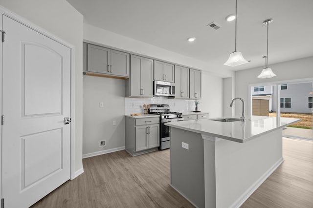 kitchen featuring stainless steel appliances, light wood-style flooring, a sink, and gray cabinets