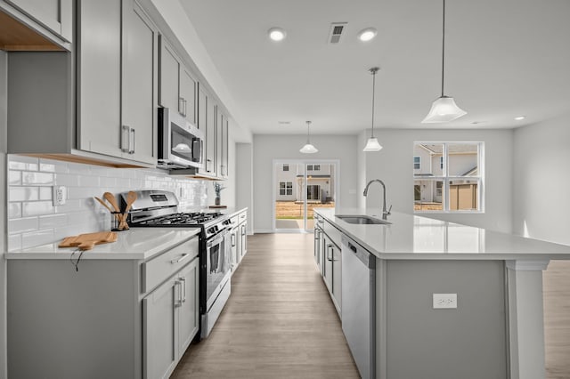 kitchen featuring visible vents, appliances with stainless steel finishes, gray cabinets, and a sink