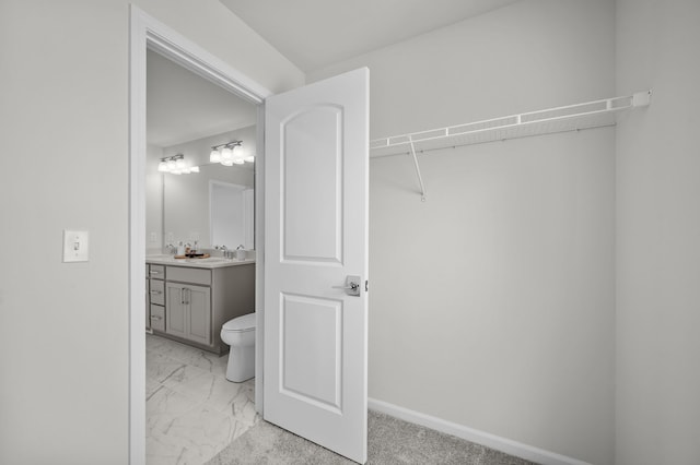 interior space with marble finish floor, toilet, vanity, and baseboards