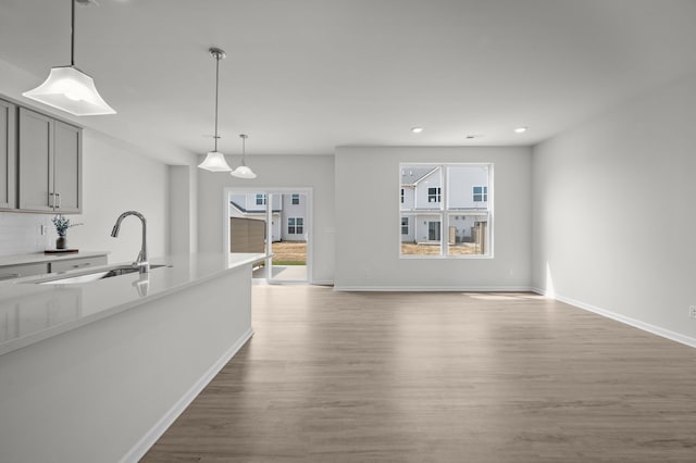unfurnished living room featuring recessed lighting, wood finished floors, baseboards, and a sink