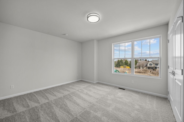 spare room with visible vents, light carpet, and baseboards