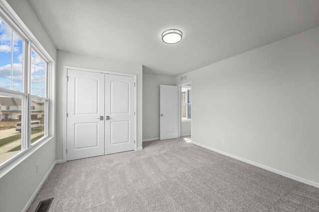 unfurnished bedroom with carpet, visible vents, baseboards, and multiple windows