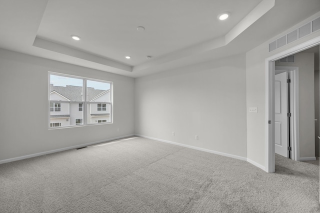 carpeted empty room featuring recessed lighting, baseboards, visible vents, and a raised ceiling