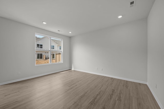 unfurnished room featuring recessed lighting, wood finished floors, visible vents, and baseboards
