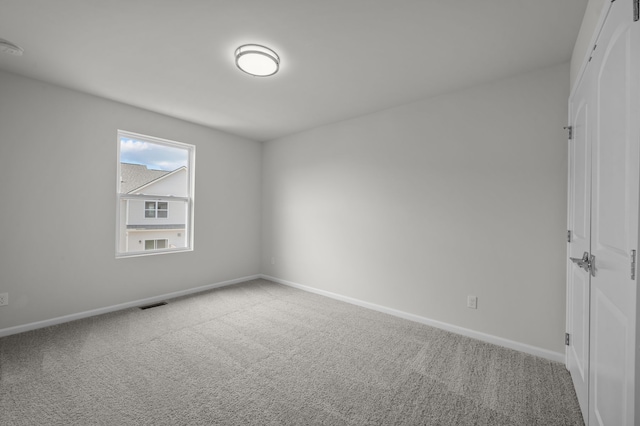 spare room featuring visible vents, carpet flooring, and baseboards