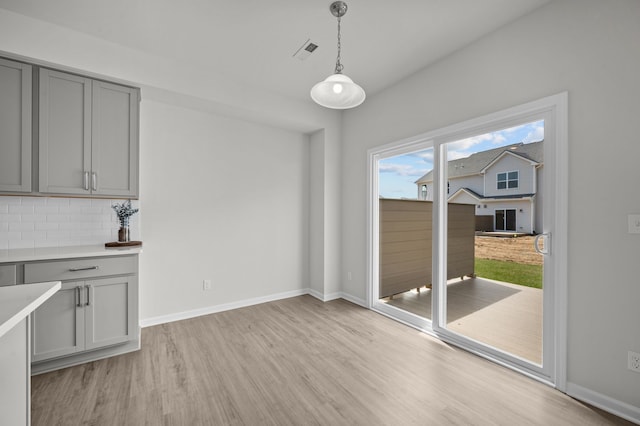 unfurnished dining area with baseboards, light wood-style floors, and visible vents