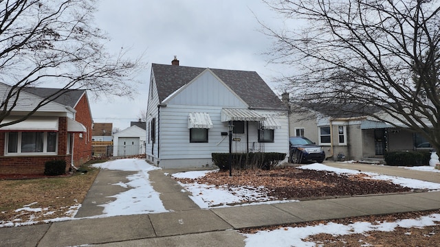 bungalow-style home featuring driveway, a chimney, board and batten siding, and roof with shingles