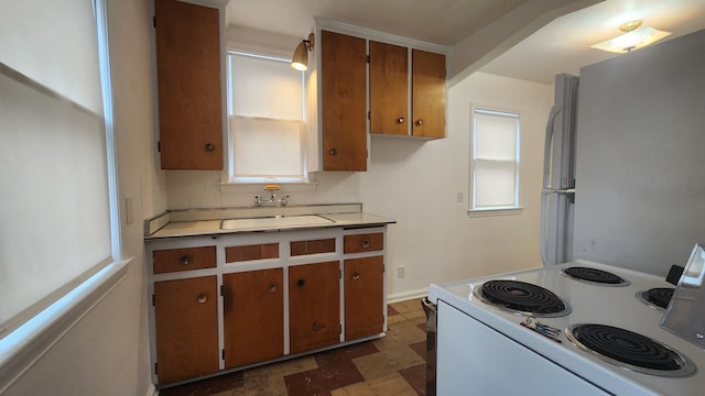 kitchen featuring white appliances, tasteful backsplash, brown cabinets, light countertops, and a sink