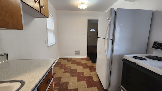 kitchen with white appliances, baseboards, visible vents, dark floors, and light countertops