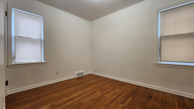 unfurnished room with wood-type flooring, visible vents, and baseboards