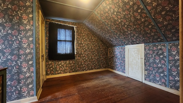 additional living space featuring wood-type flooring, vaulted ceiling, baseboards, and wallpapered walls